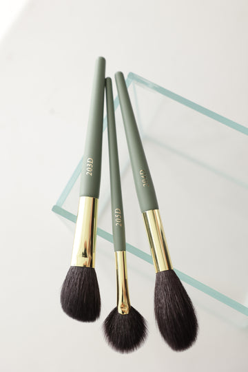 Adeline goat hair makeup brush set resting on glass surface, featuring premium natural-hair brushes for blending, contouring, and highlighting